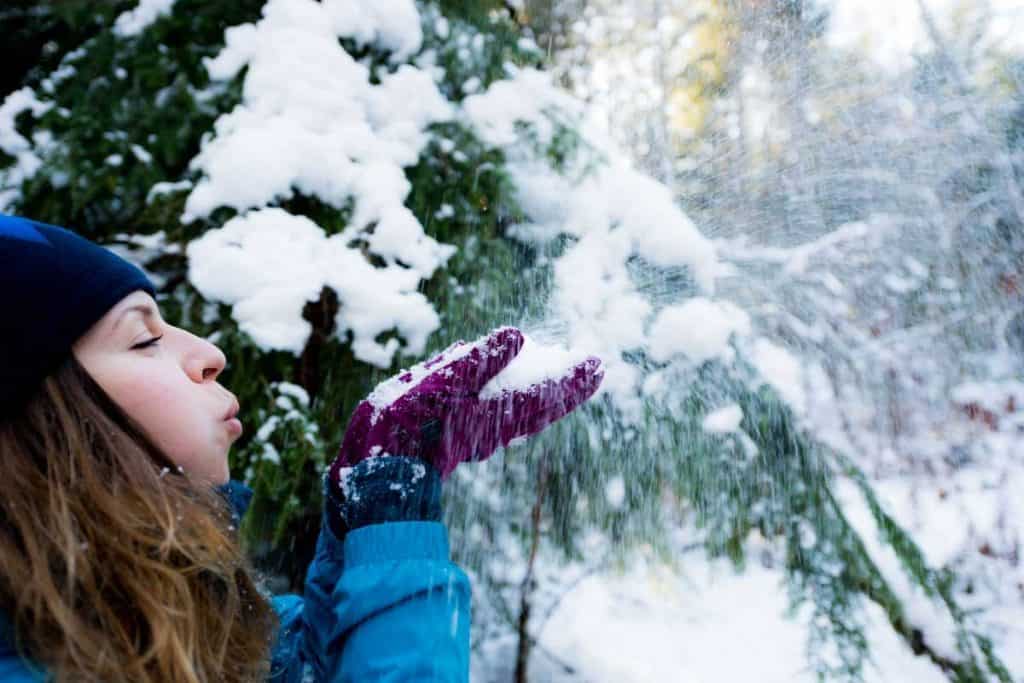Woman blowing snow in Scenic Winter Destinations, improve sleep during winter