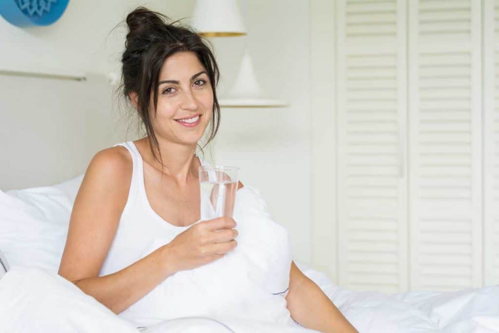 woman drinking water in bed