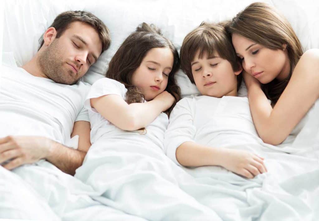 family sleeping together in bed for better sleep with age