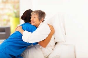 elderly woman giving a hug to home carer